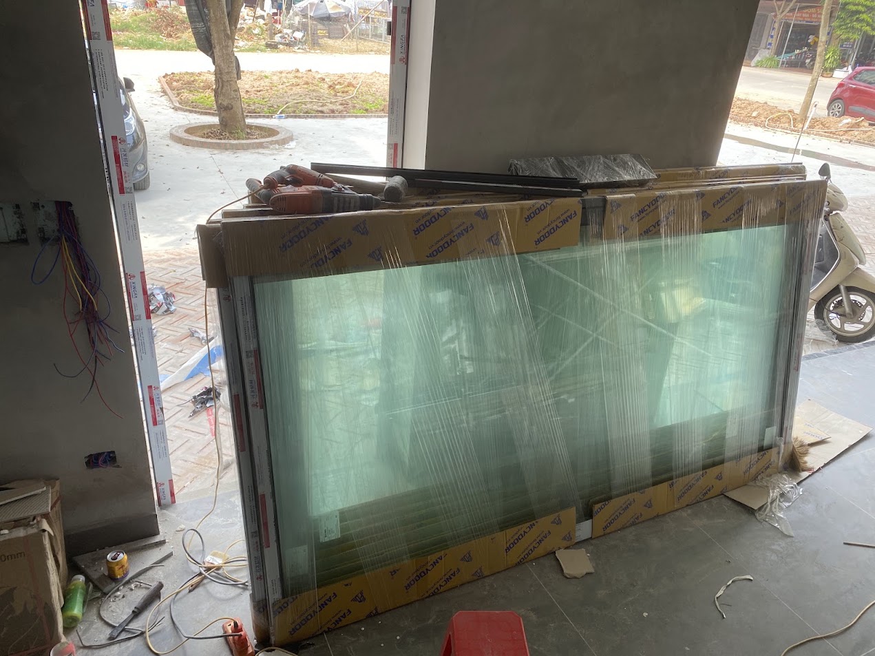 Cửa kính khung nhôm Fancydoor mới bọc nilon đặt trong nhà đang thi công xây dựng